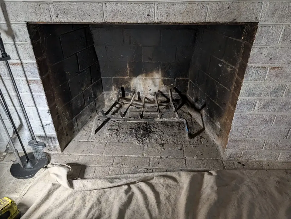 Wood-burning fireplace firebox prepared for cleaning, hearth covered with a drop cloth